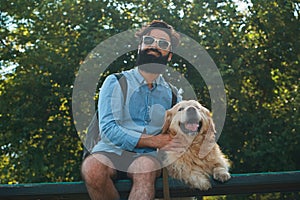 Interesting man sitting with his dog on the chair in the park en