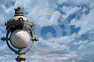 Interesting metal vintage lantern against a cloudy sky.