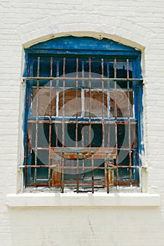 Interesting old exterior window with rusty bars and blue paint