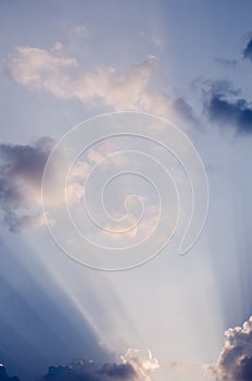 Interesting sun rays penetrating through beautiful clouds on the blue sky in a sunny day. Great vertical cloudscape backdrop