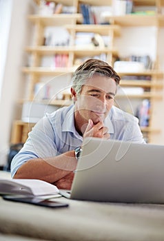 Interesting. Very interesting...a handsome mature man lying on his living room floor using a laptop.