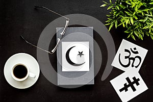 Interfaith dialogue concept. World religions symbols near book on black background top view