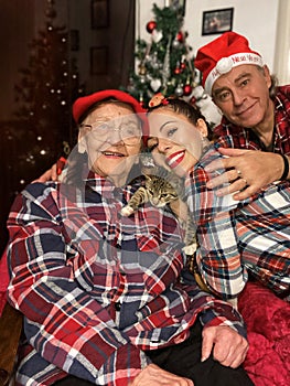 Intergenerational family gathering with kitten during Christmas in the front of Xmas tree