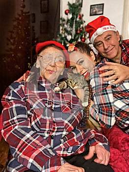 Intergenerational family gathering with kitten during Christmas in the front of Xmas tree