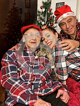 Intergenerational family gathering with kitten during Christmas in the front of Xmas tree