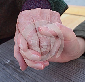 Intergenerational hands, teenage girl and elderly grandmother holding hands, in close up