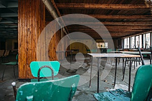 Interior of abandoned building, large dining hall with tables and chairs