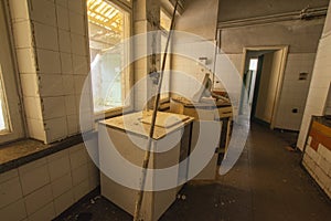 The interior of an abandoned industrial kitchen full of garbage, furniture and glasses left by users. Urbex