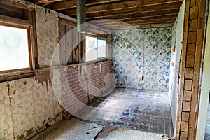 Interior of an abandoned room inside a home in Bannack Ghost town. Peeling wallpaper and cracking floorboards, with exposed beams photo