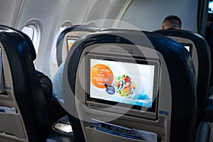 The interior of the aircraft. Empty airplane cabin. Rows of passenger seats with screens in the head restraints