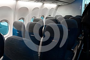 The interior of the aircraft. Empty airplane cabin. Rows of passenger seats with screens in the head restraints