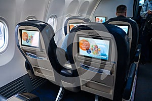 The interior of the aircraft. Empty airplane cabin. Rows of passenger seats with screens in the head restraints