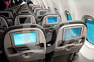 The interior of the aircraft. Empty airplane cabin. Rows of passenger seats with screens in the head restraints