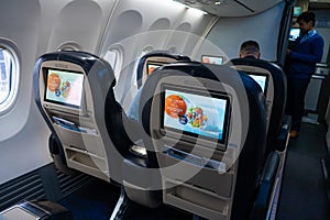 The interior of the aircraft. Empty airplane cabin. Rows of passenger seats with screens in the head restraints