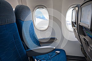 The interior of the aircraft. Empty airplane cabin. Rows of passenger seats with screens in the head restraints