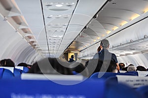 Interior of an airplane filled with passengers; air hostesses engaged in conversation,  before the safety demonstration