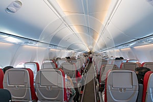 Interior of airplane with passengers on seats and stewardess in
