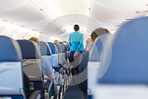 Interior of airplane with stewardess walking the aisle.