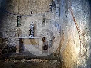The interior of an ancient, small and forgotten church. Lunigiana, Italy. With statue and crucifix.