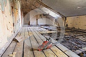 Interior of apartment during on the renovation and construction. Chainsaw on partially dismantled wooden floor and sawdust