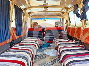 Interior of an Arab minibus for excursions through the desert. Old jeep with seats with striped fabric and curtains. Old Transfer