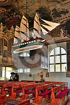 The interior of baroque church in Stegna Poland with votive sailship model under the vault.