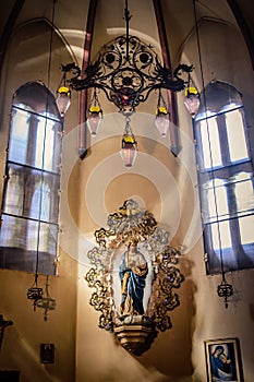 Interior of basilica of San Francesco with vintage lamps and statue of the Virgin Mary in a niche, Bologna ITALY
