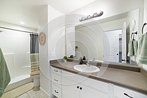 Interior of a bathroom with white marble top sink with white cabinet and mirror
