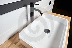 Interior of bathroom with square ceramic wash basin and black faucet. Bathroom interior sink with wooden Solid ash glued