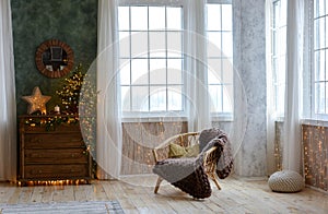 Interior of a beautiful Christmas room with a wooden chest of drawers , armchair, beautifully decorated Christmas tree on the