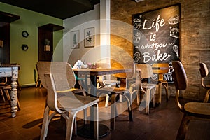 Interior of a beautiful and cozy cafe, with empty chairs and a nice quote in a wall