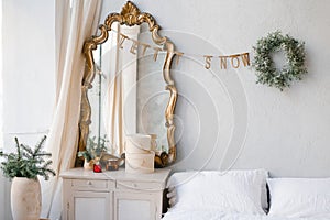 The interior of a bedroom decorated for Christmas and New Year in a Scandinavian or vintage style. A mirror over the dresser,