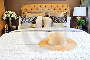 An interior bedroom design with lady hat on luxury bed.