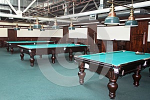 The interior of the billiard room, with green tables and lamps above them