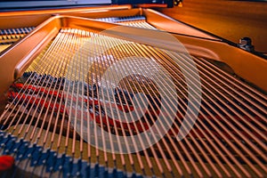 The interior of an black piano with all its details hammers,strings and keys.Golden interior with shades of red