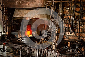 Interior of Blacksmith forge with tools hanging on wall and anvil and hammer ready to be used. Furnace formant