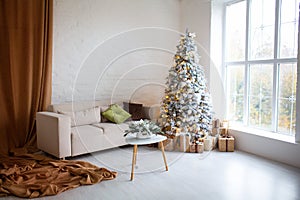 Interior of bright modern living room with comfortable sofa decorated with Christmas tree and gifts