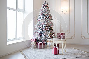 Interior of bright modern living room with comfortable sofa decorated with Christmas tree and gifts