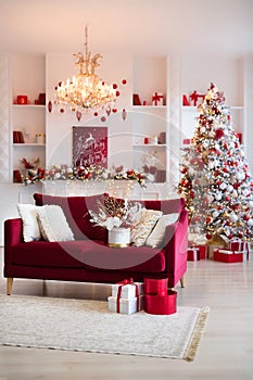 Interior of bright modern living room with fireplace, chandelier and comfortable sofa decorated with Christmas tree and