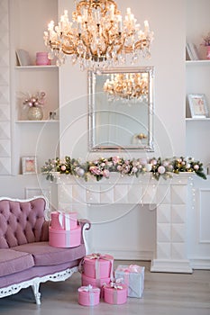 Interior of bright modern living room with fireplace and comfortable sofa decorated with Christmas tree and gifts