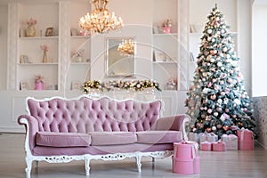 Interior of bright modern living room with fireplace and comfortable sofa decorated with Christmas tree and gifts