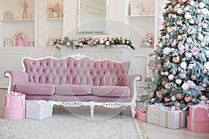 Interior of bright modern living room with fireplace and comfortable sofa decorated with Christmas tree and gifts