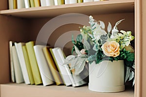 Interior of a bright studio room, decorated with spring flowers, a shelf with books, antique decor