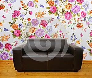Interior with brown leather couch against floral wall