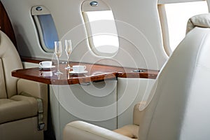 Interior of a business class of a commercial passenger plane, an armchair and a window, a table and a cocktail glass