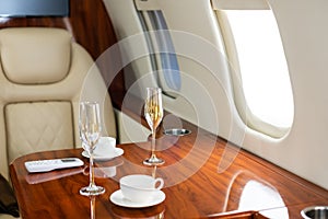 Interior of a business class of a commercial passenger plane, an armchair and a window, a table and a cocktail glass