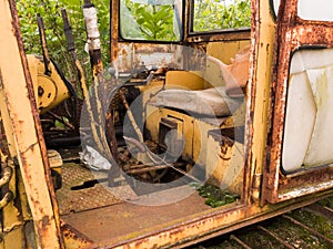 Interior of cabin with lever, joystick and seat of abandoned deserted old rusty bulldozer, vintage industrial heavy machine,
