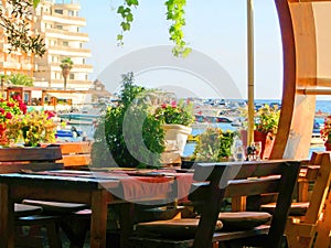 Interior cafe on the coast, an empty wooden table and chairs decorated with plants. The veranda of the seaside cafe