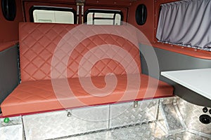 The interior of the car in the back of a van converted into a motor home for off-road and travel with a brown leather interior, a