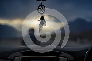 Interior of a car featuring a dream catcher draping from the windshield